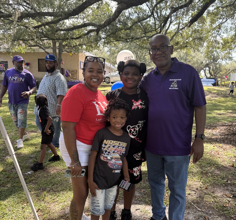 Bishop Lewis with families and children outdoors on the church grounds