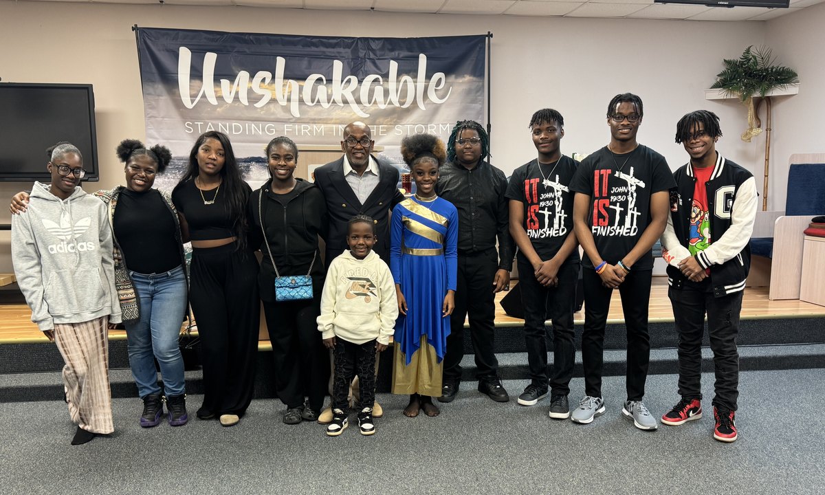 Bishop Michael W. Lewis, Sr. and the First Victory Cathedral congregation standing under the Unshakable banner